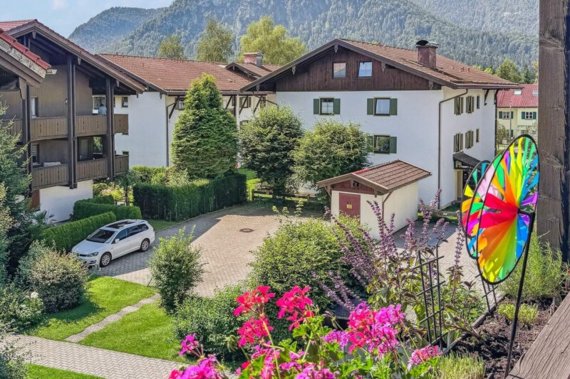 Blick vom Balkon der Ferienwohnung Chiemgauzeit mit idyllischem Hinterhof und beeindruckendem Panorama der Alpen im Hintergrund.