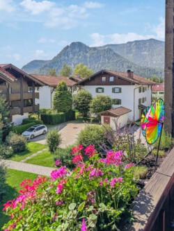 Blick vom Balkon der Ferienwohnung Chiemgauzeit mit idyllischem Hinterhof und beeindruckendem Panorama der Alpen im Hintergrund.